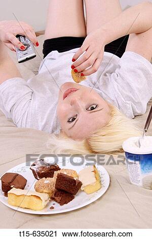 Young woman having cakes on bed watching tv, a unhealth diet, habit View Large Photo Image Stock Image - Young woman having cakes on bed watching tv, a unhealth diet, habit. Fotosearch
