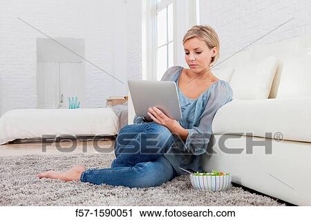 Young woman having lunch while socializing on her tablet computer View Large Photo Image Stock Image - Young woman having lunch while socializing on her tablet computer. Fotosearch
