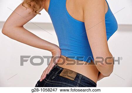 Stock Photo - young woman ( head invisible )in blue sports top, holding her back with one hand for backache. Fotosearch