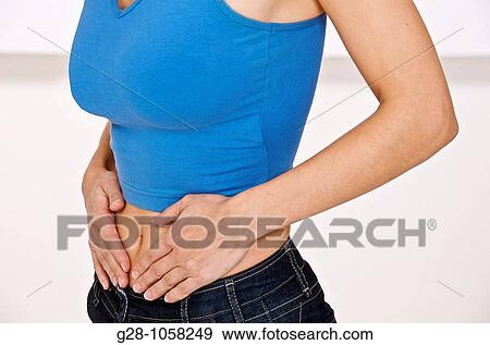 Stock Photo - young woman ( head invisible ) in blue sports top holding her stomach with her hands, suffering from periods or stomach ache pains. Fotosearch
