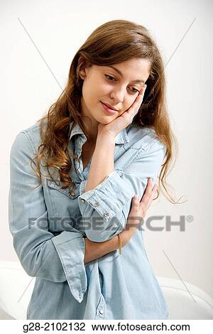 Young woman, her head in her hand thoughtful, in a blue jeans shirt View Large Photo Image Stock Image - Young woman, her head in her hand thoughtful, in a blue jeans shirt. Fotosearch