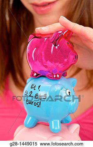 Stock Photography - Young woman holding 3 brightly colored piggy money boxes. Fotosearch