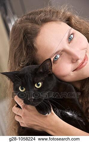 Picture - young woman holding a black cat, risk of allergy. Fotosearch
