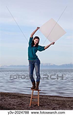Young woman holding a blank sign, in front of the Great Salt Lake. View Large Photo Image Stock Photo - Young woman holding a blank sign, in front of the Great Salt Lake.. Fotosearch