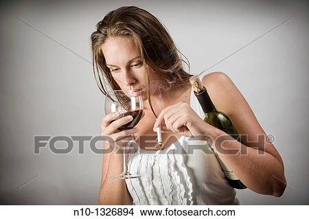 Young woman holding a bottle and glass of wine, and a cigarette View Large Photo Image Picture - Young woman holding a bottle and glass of wine, and a cigarette. Fotosearch