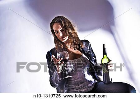 Stock Photography - Young woman holding a bottle and glass of wine, and a cigarette. Fotosearch
