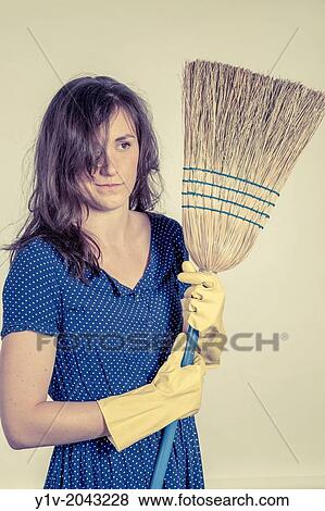 Young woman holding a broom. View Large Photo Image Stock Photo - Young woman holding a broom.. Fotosearch