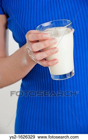 Young woman holding a glass of milk View Large Photo Image Stock Photo - Young woman holding a glass of milk. Fotosearch