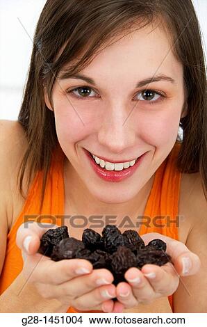 Young woman holding a handful of dried prunes View Large Photo Image Picture - Young woman holding a handful of dried prunes. Fotosearch