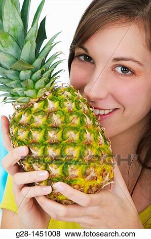 Young woman holding a pineapple View Large Photo Image Stock Photo - Young woman holding a pineapple. Fotosearch