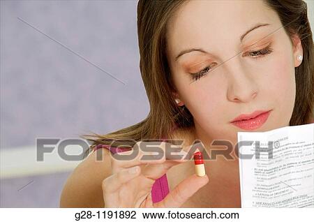 Young woman holding a red and white medical tablet and reading a prescription View Large Photo Image Stock Image - Young woman holding a red and white medical tablet and reading a prescription. Fotosearch