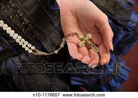 Young woman holding a rosary in her hand View Large Photo Image Stock Photo - Young woman holding a rosary in her hand. Fotosearch