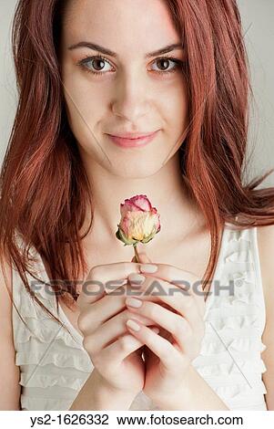 Stock Image - Young woman holding a rose. Fotosearch