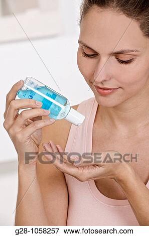 young woman holding a small bottle of blue desinfectant for hands ready to apply it to kill germs View Large Photo Image Stock Photo - young woman holding a small bottle of blue desinfectant for hands ready to apply it to kill germs. Fotosearch