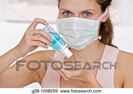 young woman holding a small bottle of blue desinfectant for hands ready to apply it to kill germs View Large Photo Image Stock Photo - young woman holding a small bottle of blue desinfectant for hands ready to apply it to kill germs. Fotosearch