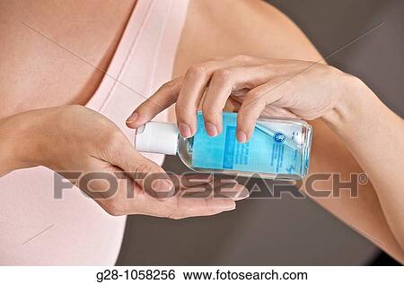 young woman holding a small bottle of blue desinfectant for hands ready to apply it to kill germs head invisible View Large Photo Image Stock Photograph - young woman holding a small bottle of blue desinfectant for hands ready to apply it to kill germs head invisible. Fotosearch