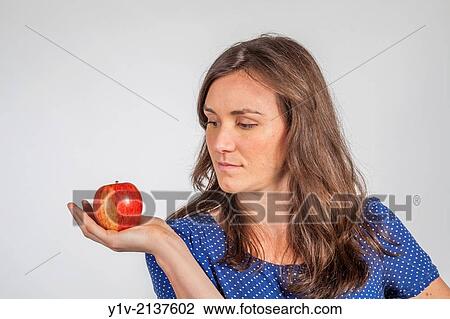 Stock Image - Young woman holding an apple.. Fotosearch