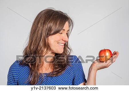 Stock Image - Young woman holding an apple.. Fotosearch