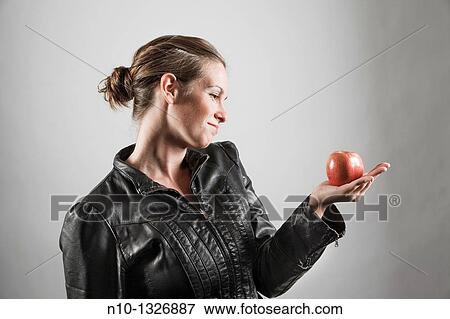 Young woman holding an apple View Large Photo Image Stock Photo - Young woman holding an apple. Fotosearch