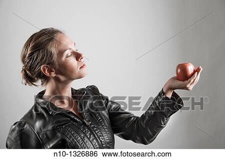 Young woman holding an apple View Large Photo Image Stock Photograph - Young woman holding an apple. Fotosearch