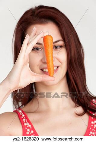 Young woman holding an organic carrot View Large Photo Image Stock Image - Young woman holding an organic carrot. Fotosearch