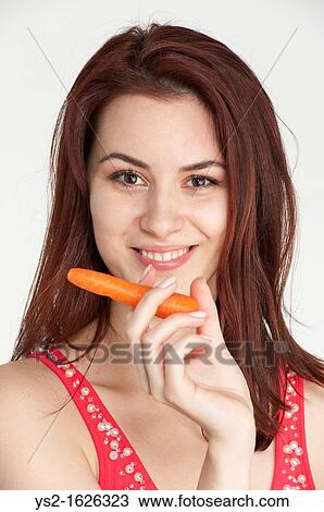 Young woman holding an organic carrot like a cigar View Large Photo Image Stock Image - Young woman holding an organic carrot like a cigar. Fotosearch