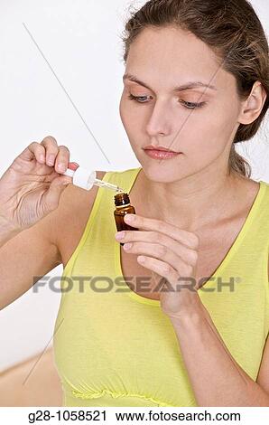 young woman holding asmall bottle of organic essential oil, with dropper View Large Photo Image Stock Image - young woman holding asmall bottle of organic essential oil, with dropper. Fotosearch