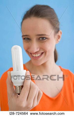 Picture - Young woman holding compact fluorescent bulb, portrait. Fotosearch