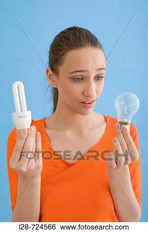Young woman holding compact fluorescent bulb, portrait View Large Photo Image Stock Photograph - Young woman holding compact fluorescent bulb, portrait. Fotosearch
