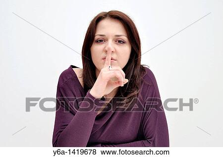 Young woman holding finger up to mouth View Large Photo Image Stock Photo - Young woman holding finger up to mouth. Fotosearch