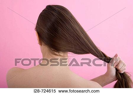 Stock Photography - Young woman holding hair, studio shot. Fotosearch