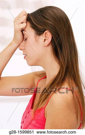 Young woman holding her forehead with her hand and suffering from a headache View Large Photo Image Stock Image - Young woman holding her forehead with her hand and suffering from a headache. Fotosearch