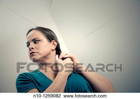 Stock Image - Young woman holding her hair. Fotosearch
