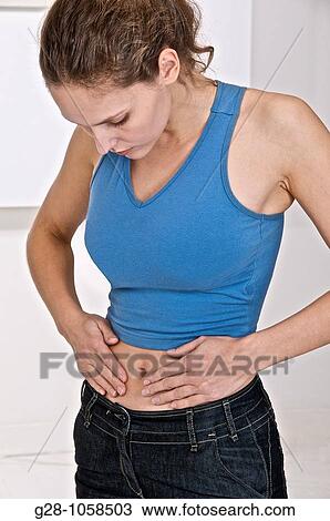 young woman holding her stomach and suffering from periods or stomach pains View Large Photo Image Stock Image - young woman holding her stomach and suffering from periods or stomach pains. Fotosearch