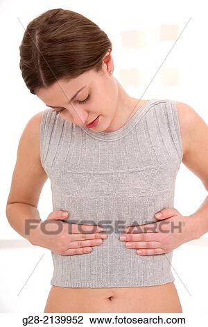 young woman holding her stomach and ribs for pain View Large Photo Image Stock Image - young woman holding her stomach and ribs for pain. Fotosearch