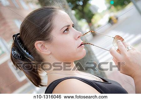 Stock Photograph - Young woman holding her sunglasses. Fotosearch