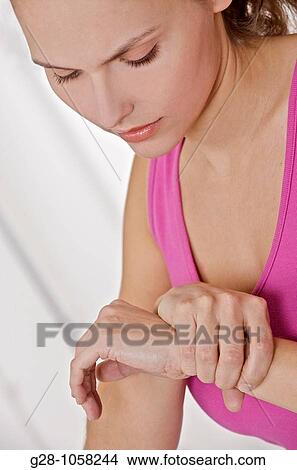 young woman holding her wrist, suffering from twisted wrist or rheumatism View Large Photo Image Picture - young woman holding her wrist, suffering from twisted wrist or rheumatism. Fotosearch