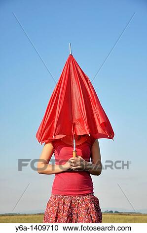 Stock Image - Young woman holding red umbrella. Fotosearch