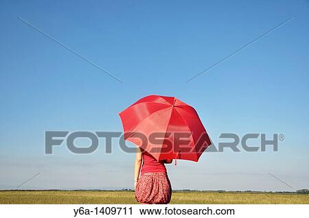 Stock Image - Young woman holding red umbrella. Fotosearch