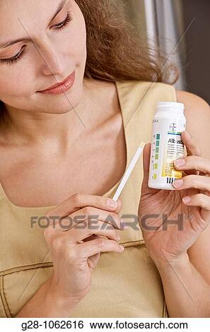 Stock Photograph - young woman holding self urine test tube analysis. Fotosearch