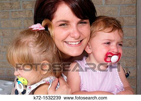 Stock Photo - Young woman holding several toddlers. Fotosearch
