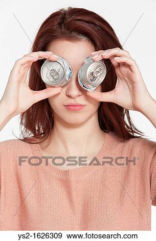 Young woman holding two crushed drink cans in front of face View Large Photo Image Stock Photo - Young woman holding two crushed drink cans in front of face. Fotosearch