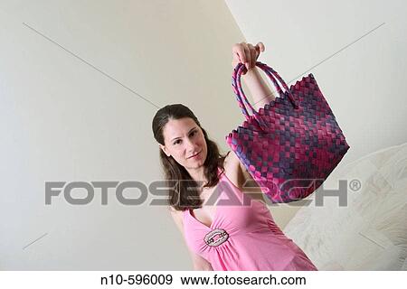 Stock Photo - Young woman holding up her handbag.. Fotosearch