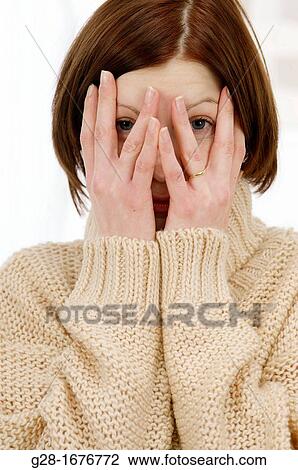 Young woman in a beige turtleneck pullover, looking through her fingers because she is shy or afraid or stressed View Large Photo Image Stock Image - Young woman in a beige turtleneck pullover, looking through her fingers because she is shy or afraid or stressed. Fotosearch