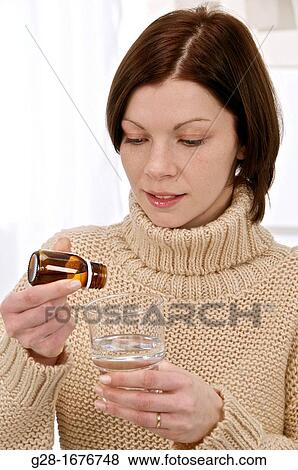 Young woman in a beige turtleneck pullover, pouring drops of essential oil into a glass View Large Photo Image Stock Photo - Young woman in a beige turtleneck pullover, pouring drops of essential oil into a glass. Fotosearch