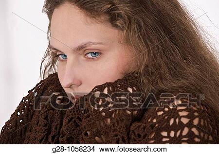 Picture - young woman in a brown shawl feeling bad with a cold or the flue. Fotosearch