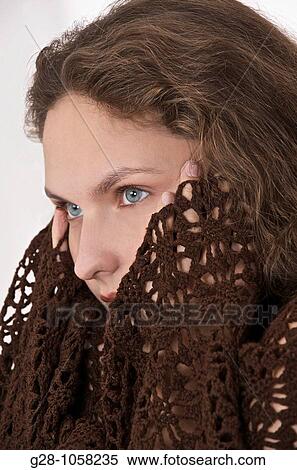 Stock Photography - young woman in a brown shawl holding her temples because of a headache. Fotosearch