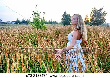 Picture - Young woman in a wheat field in a russian village, Kirillovka, Russian Federation. Fotosearch
