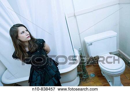 Young woman, in an evening dress, sitting on the edge of her bathtub. View Large Photo Image Stock Photo - Young woman, in an evening dress, sitting on the edge of her bathtub.. Fotosearch