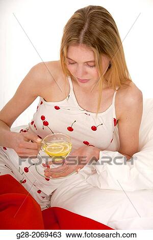 young woman in bed holding a transparent cup of herbal teal with a slice of lemon View Large Photo Image Stock Image - young woman in bed holding a transparent cup of herbal teal with a slice of lemon. Fotosearch